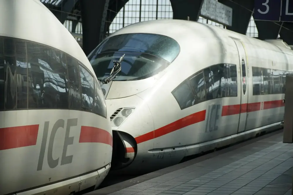 Two silver ICE trains lined up at a station platform with large curved cockpit windows and a red stripe along the side.